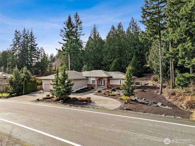 single story home with a garage, concrete driveway, and brick siding