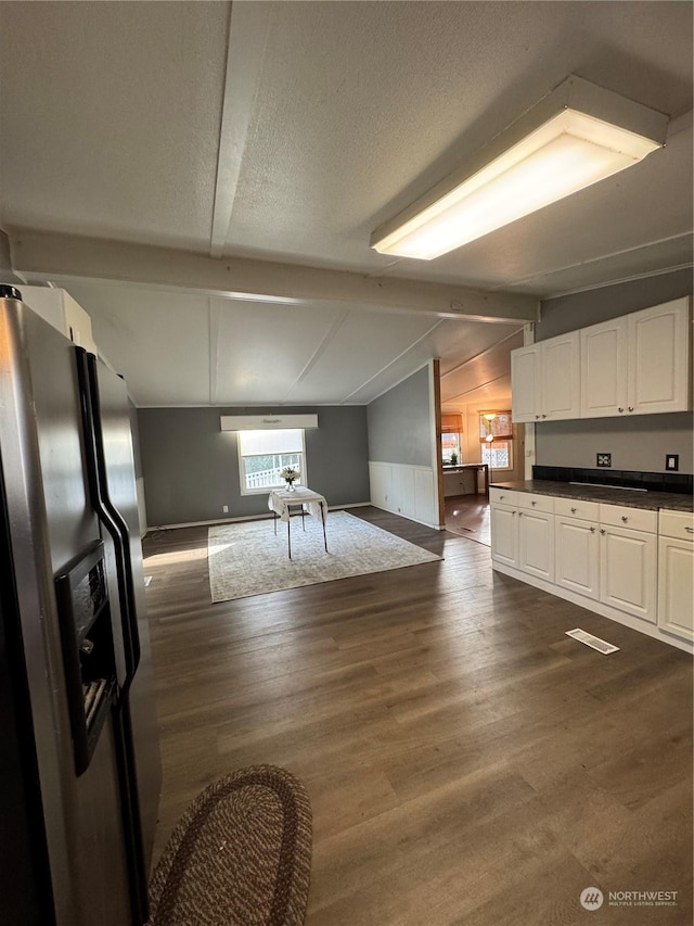 kitchen featuring white cabinets, stainless steel fridge with ice dispenser, a healthy amount of sunlight, and lofted ceiling with beams