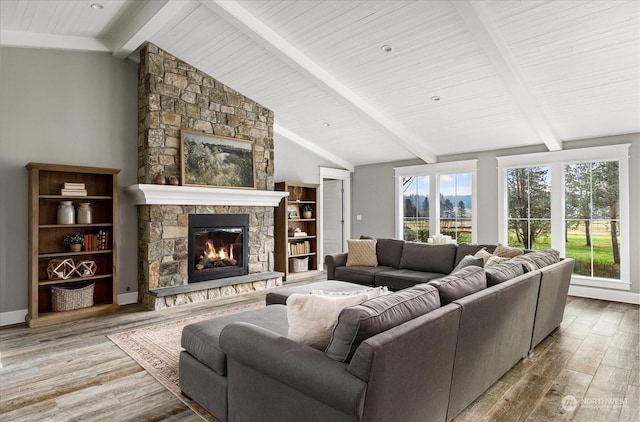 living room featuring hardwood / wood-style floors, a stone fireplace, and vaulted ceiling with beams