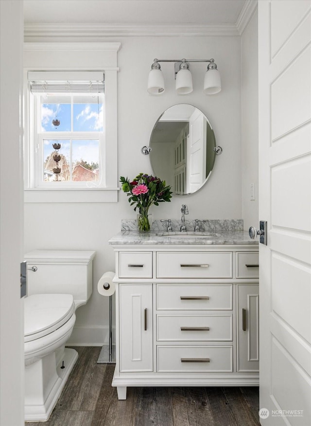 bathroom featuring toilet, vanity, ornamental molding, and hardwood / wood-style floors