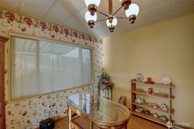 dining room with a chandelier, wood finished floors, and wallpapered walls