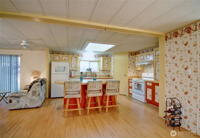 dining area featuring a skylight, light wood-style flooring, and a ceiling fan