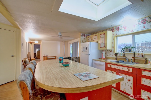 kitchen with white appliances, light countertops, a sink, and light wood-style flooring