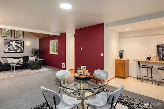 dining area featuring light carpet and vaulted ceiling with beams