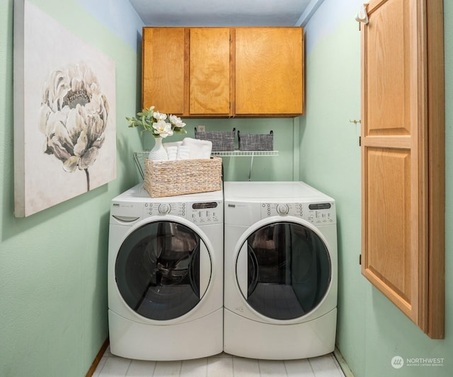 clothes washing area featuring washing machine and clothes dryer and cabinets