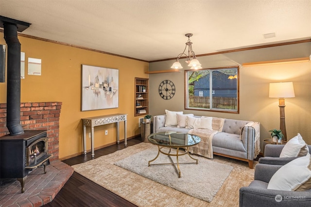 living room featuring dark wood-type flooring, an inviting chandelier, crown molding, and a wood stove