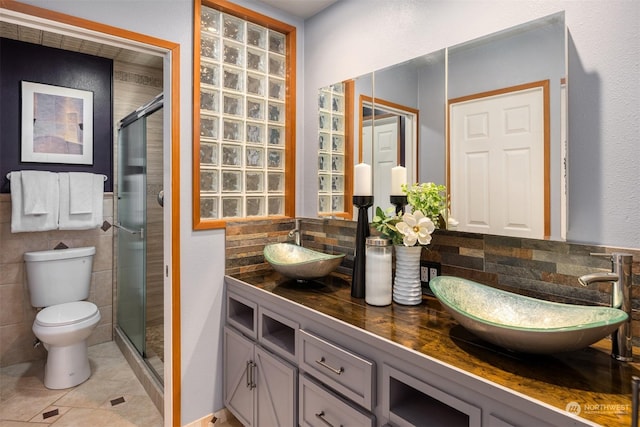 bathroom featuring tile patterned flooring, toilet, backsplash, an enclosed shower, and vanity