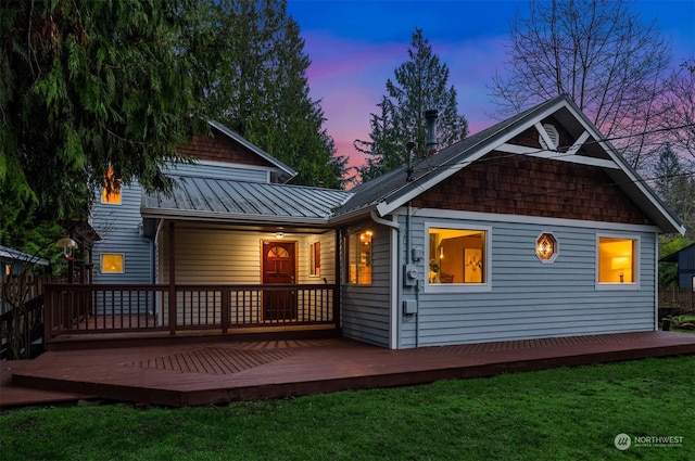 back house at dusk with a yard and a wooden deck