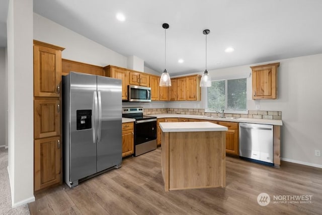 kitchen with a center island, stainless steel appliances, hanging light fixtures, vaulted ceiling, and light hardwood / wood-style flooring