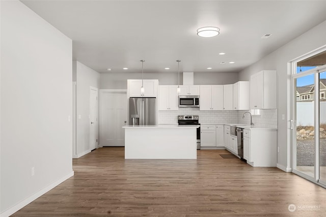 kitchen featuring stainless steel appliances, a center island, white cabinetry, a wealth of natural light, and pendant lighting