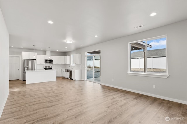 unfurnished living room featuring sink, a wealth of natural light, and light hardwood / wood-style floors