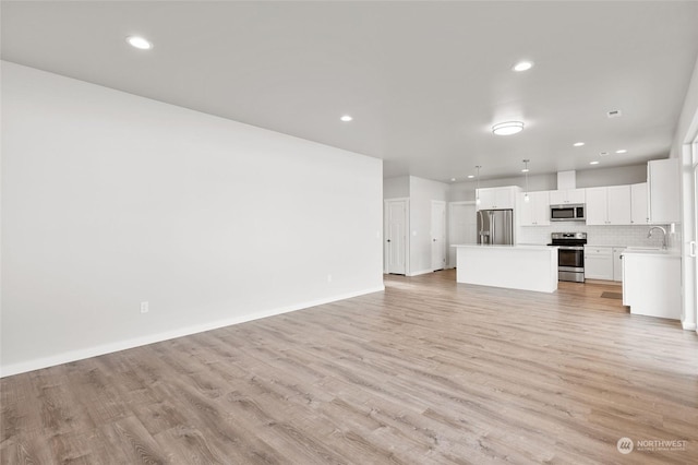 unfurnished living room featuring sink and light wood-type flooring