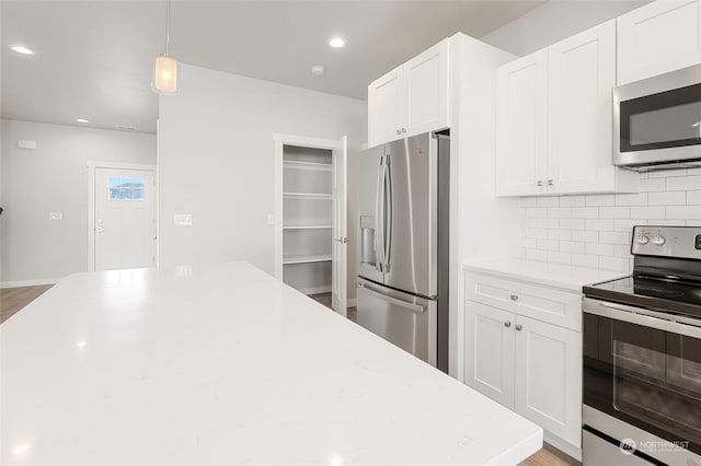 kitchen with light stone counters, hanging light fixtures, stainless steel appliances, tasteful backsplash, and white cabinets