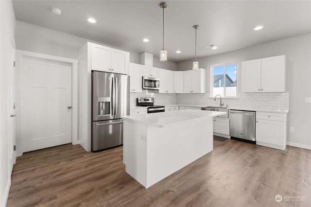 kitchen featuring white cabinets, stainless steel appliances, a kitchen island, and pendant lighting