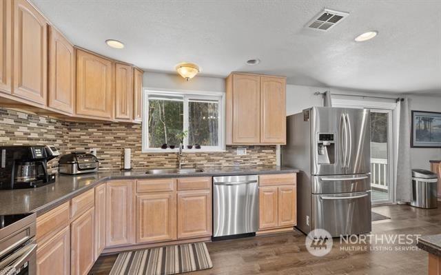 kitchen with stainless steel appliances, light brown cabinetry, tasteful backsplash, and sink