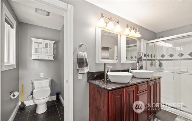 bathroom featuring tile patterned flooring, toilet, a shower with door, and vanity