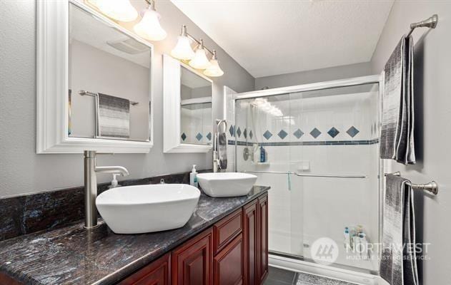 bathroom with a shower with shower door and vanity