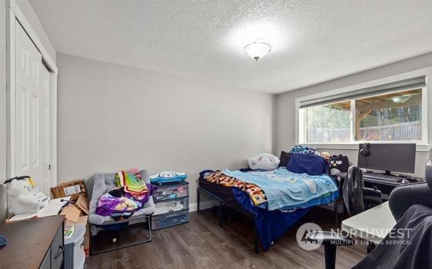 bedroom with a textured ceiling, a closet, and dark hardwood / wood-style floors