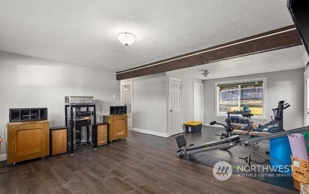 exercise area featuring dark wood-type flooring and a textured ceiling