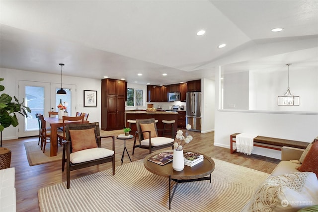 living room with french doors, light wood-type flooring, and lofted ceiling