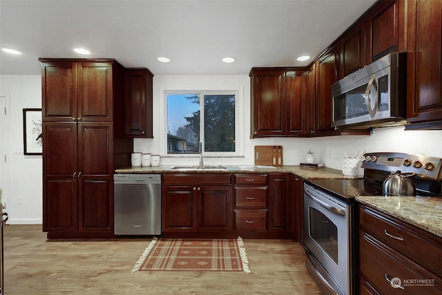 kitchen featuring light stone countertops, sink, light wood-type flooring, and appliances with stainless steel finishes