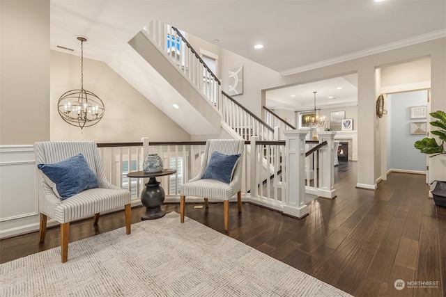 living area featuring ornamental molding, lofted ceiling, a chandelier, and wood-type flooring