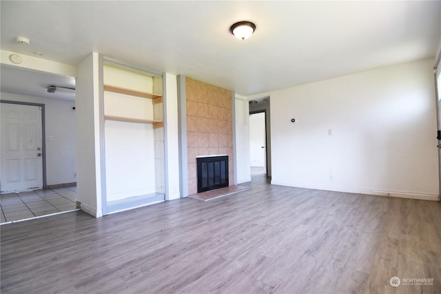 unfurnished living room featuring wood-type flooring and a tile fireplace