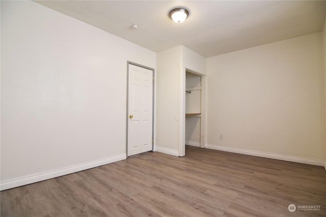 unfurnished bedroom with a textured ceiling, a closet, and hardwood / wood-style flooring