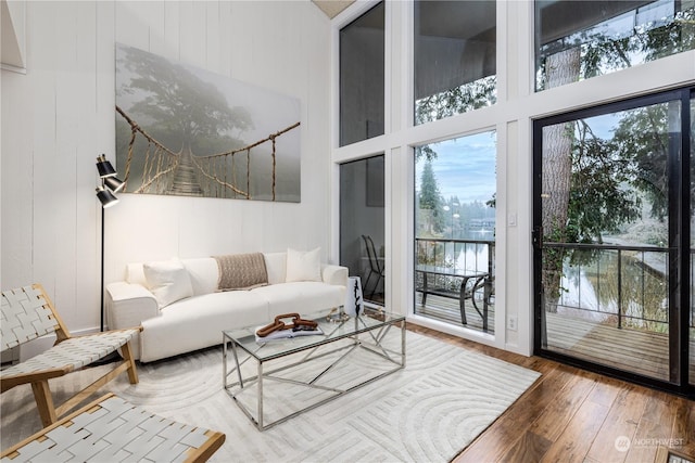 living room with a high ceiling, hardwood / wood-style floors, and a water view