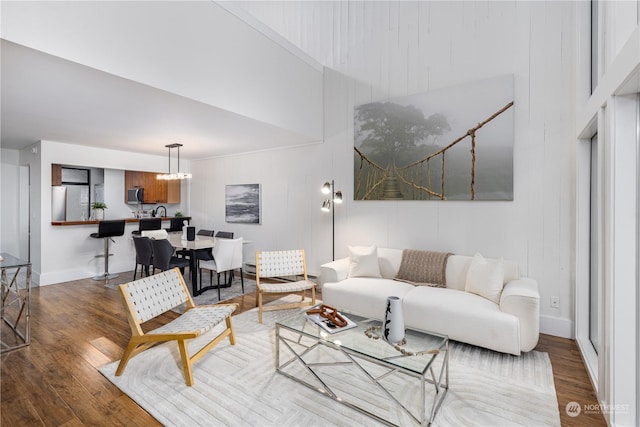 living room featuring wood-type flooring, a towering ceiling, and a chandelier