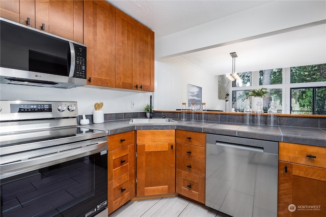 kitchen with light tile patterned floors, sink, stainless steel appliances, and a textured ceiling