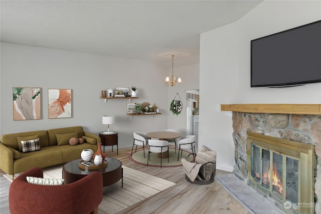 living room with a notable chandelier, a stone fireplace, and hardwood / wood-style flooring