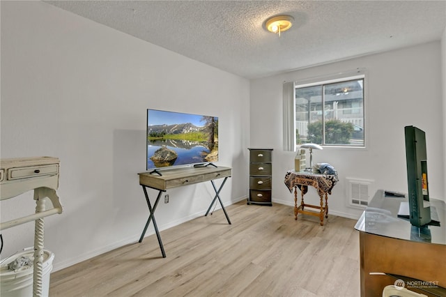 home office featuring a textured ceiling and light hardwood / wood-style flooring