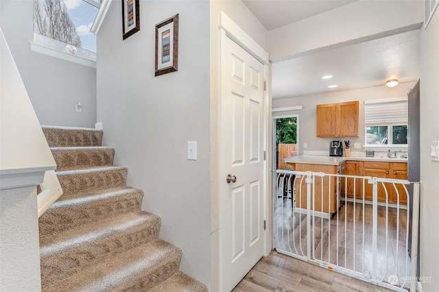 stairway with sink and hardwood / wood-style flooring