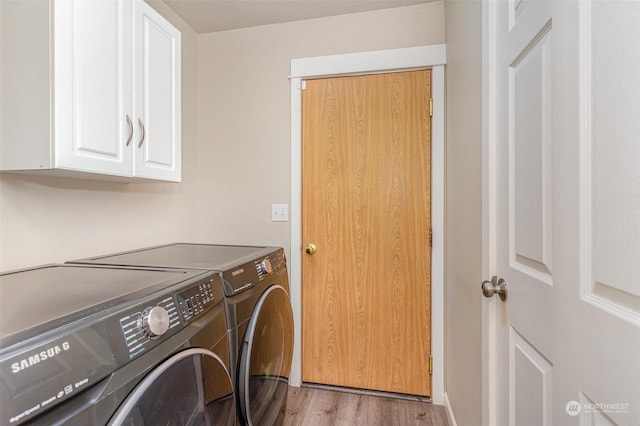 clothes washing area featuring washing machine and clothes dryer, light wood-type flooring, and cabinets