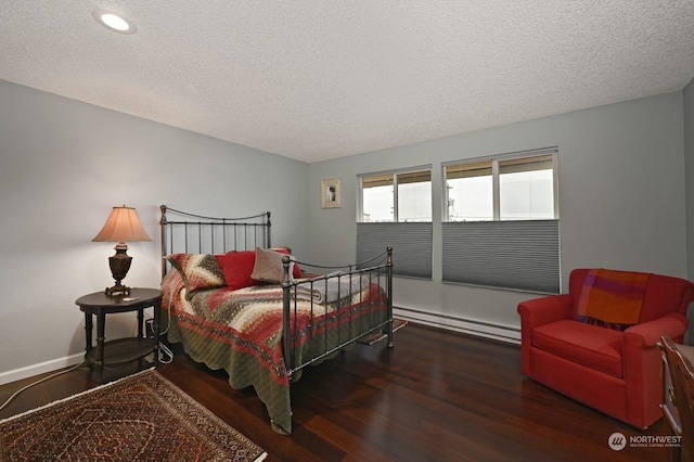 bedroom with dark wood-type flooring, baseboard heating, and a textured ceiling