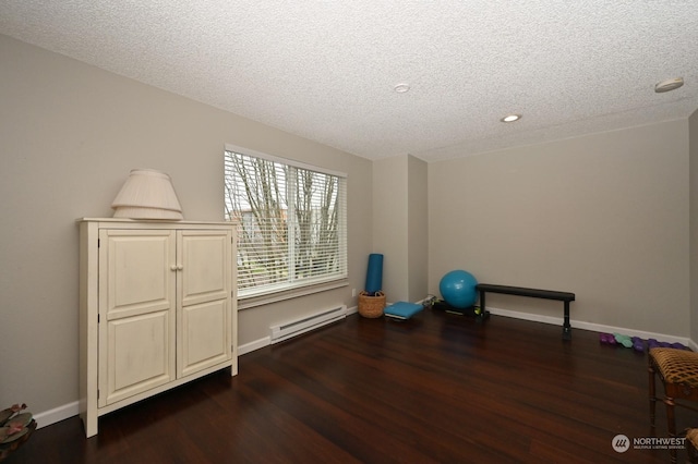 workout area with baseboard heating, a textured ceiling, and dark hardwood / wood-style floors