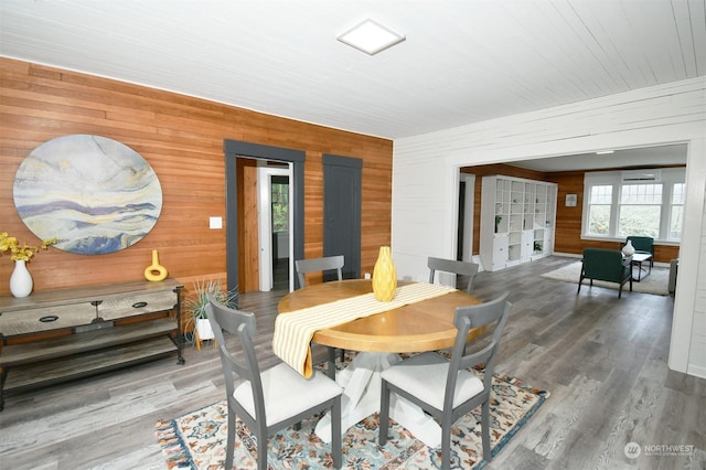 dining space featuring hardwood / wood-style floors and wood walls