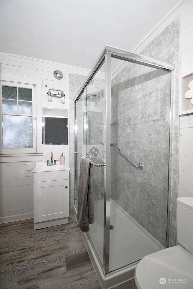 bathroom with hardwood / wood-style floors, wooden walls, an enclosed shower, and vanity