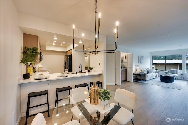 dining area with sink, light hardwood / wood-style flooring, and a notable chandelier