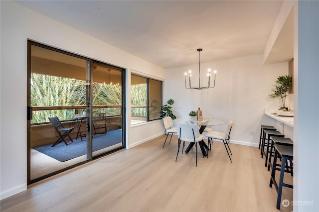 dining space featuring light wood-type flooring and an inviting chandelier