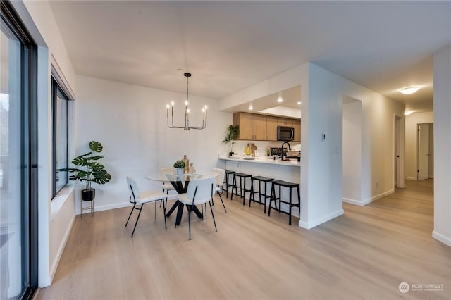 dining area with light hardwood / wood-style floors, sink, and a chandelier