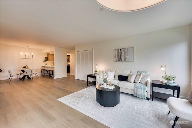 living room with light wood-type flooring and a notable chandelier