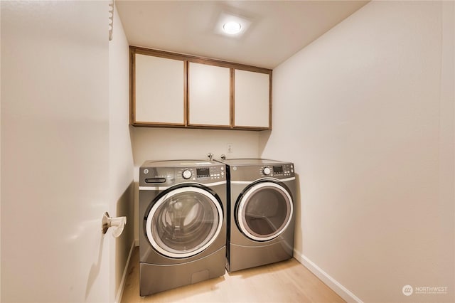 laundry room featuring washer and clothes dryer, light hardwood / wood-style floors, and cabinets