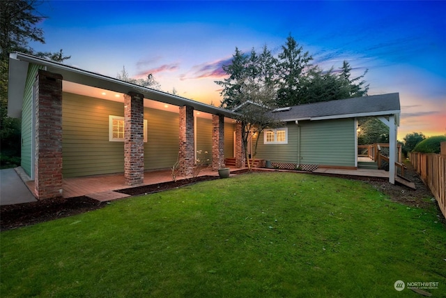 back house at dusk featuring a yard