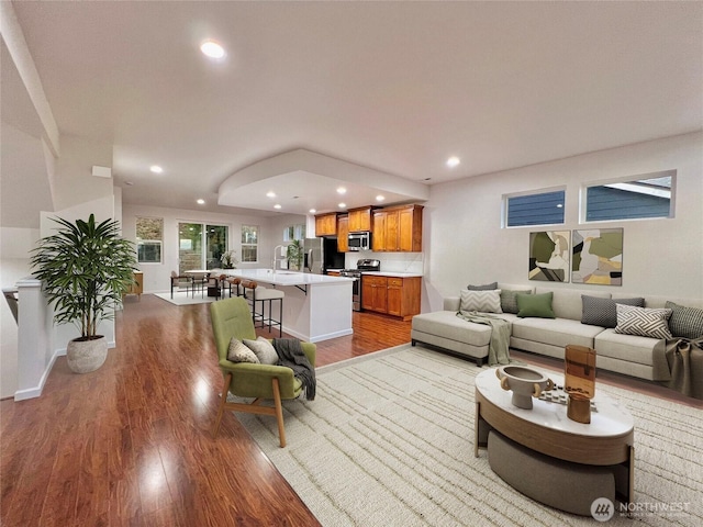 living room with recessed lighting, baseboards, and wood finished floors