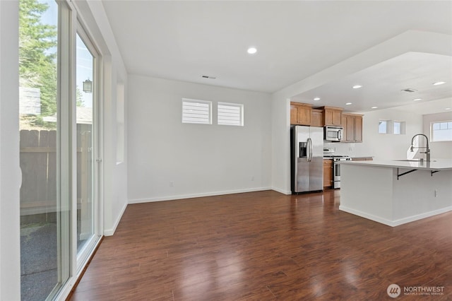 kitchen featuring appliances with stainless steel finishes, a breakfast bar area, dark wood-type flooring, and a sink