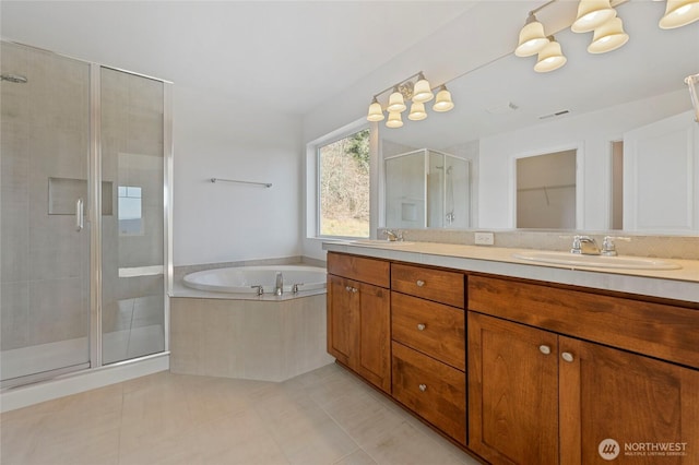 bathroom with double vanity, a garden tub, a stall shower, and a sink