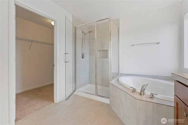 full bath featuring vanity, a garden tub, a stall shower, and a spacious closet