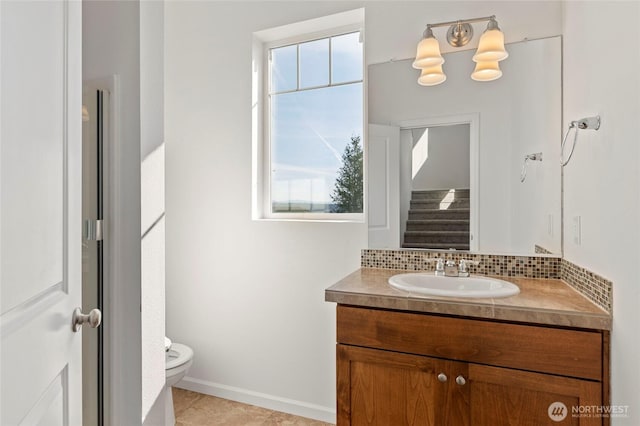 bathroom with decorative backsplash, toilet, vanity, and baseboards